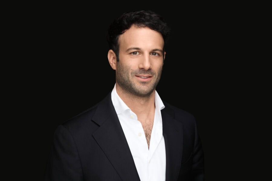 Luca Lelli wearing a dark suit and white shirt. He has a slight smile and displays a professional demeanor.